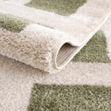 Close-up of the Beynon Green Washable Area Rug showing its lime green and cream geometric pattern and soft, plush texture. Fold