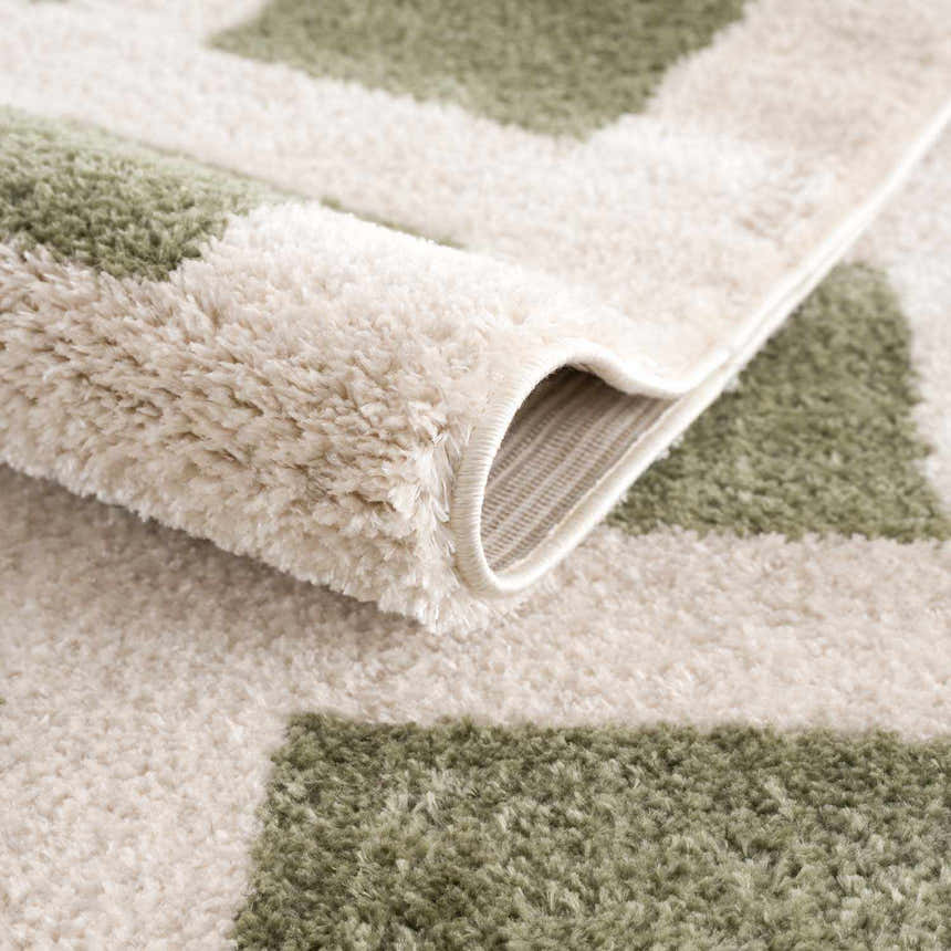 Close-up of the Beynon Green Washable Area Rug showing its lime green and cream geometric pattern and soft, plush texture. Fold