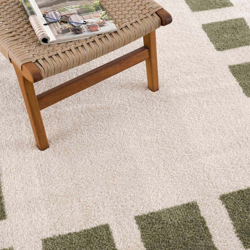 Close-up of the Beynon Green Washable Area Rug with a geometric square pattern and soft, textured pile. Styleshot