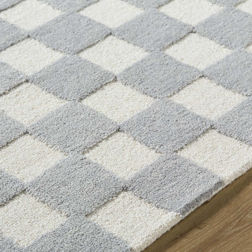 Close-up of the Amparo Medium Gray Area Rug showing its ivory and gray diamond pattern and hand-tufted wool texture. Texture