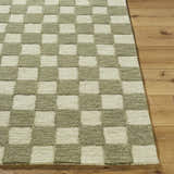 Close up of the Amparo Olive Area Rug showing a beige and olive checkerboard pattern and wool texture. Front