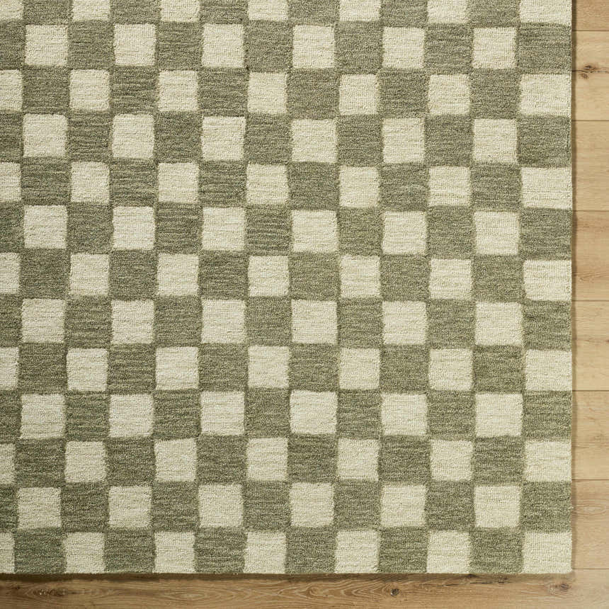 Close-up of the hand-tufted Amparo Olive Area Rug, a beige and olive wool rug with a checkerboard pattern on wood floor. Corner
