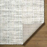 Close-up of the textured Yidia White area rug showing off-white, light gray, and black tones. Fold