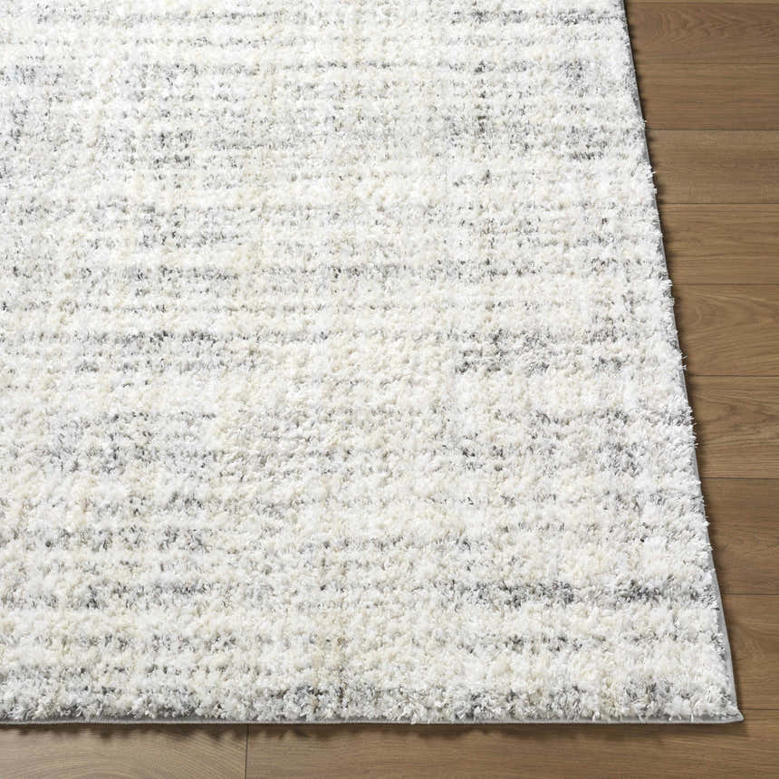 Close-up of the Yidia White rug showing its off-white, light gray, and black hues and soft, textured polyester weave. Front