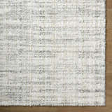 Close-up of the Yidia White rug, a machine-woven polyester rug with off-white, light gray, and black horizontal striations. Corner