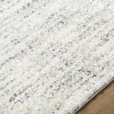 Close up of the textured Yidia White Solid Area Rug with off white, light gray, and black tones. Texture