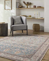 Living room scene with a gray chair and the Bahram Vintage Flat Pile Washable Rug in black, cream, blue, and red tones. Roomscene-Rectangle