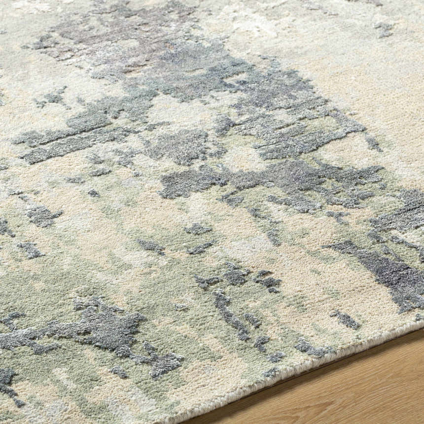 Close up of the Bued Handmade Wool-Blend Rug showing beige, gray, and teal abstract pattern and hand-knotted texture. Pile