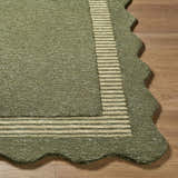 Close up of Wone Green Border Hand Tufted Wool Area Rug with a striped border and scalloped edge on hardwood floor. Front