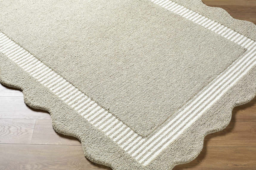 Close-up of the hand-tufted Fanae Beige Border Wool Area Rug showing texture, striped border, and scalloped edge. Corner