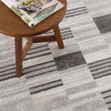 Close-up of the Bronka Broken-Striped Area Rug. Geometric design in black, gray, and off white. Machine woven texture. Styleshot