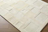 Close up of the Botham Area Rug, a hand-tufted wool rug in beige, cream, and ivory with a contemporary geometric pattern. Corner