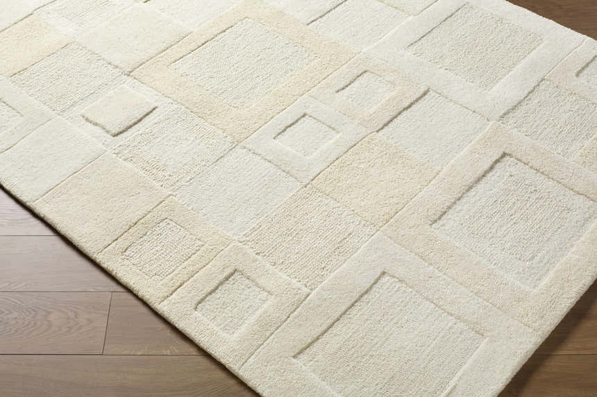 Close up of the Botham Area Rug, a hand-tufted wool rug in beige, cream, and ivory with a contemporary geometric pattern. Corner
