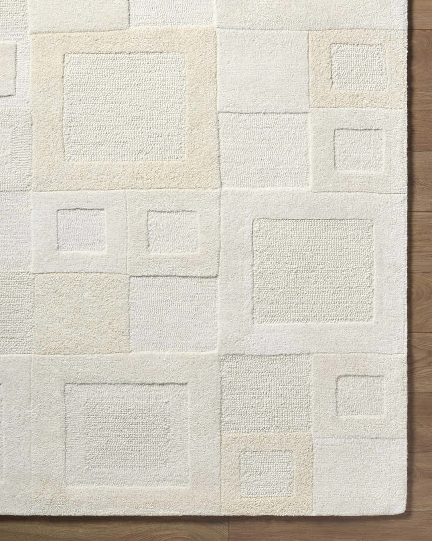 Close-up of the Botham Area Rug. Hand-tufted wool rug in a geometric square pattern, beige, cream, ivory, and tan colors. Corner