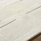Close up of the Botham Area Rug, a hand-tufted wool rug in cream, beige, and ivory with a subtle geometric pattern. Texture