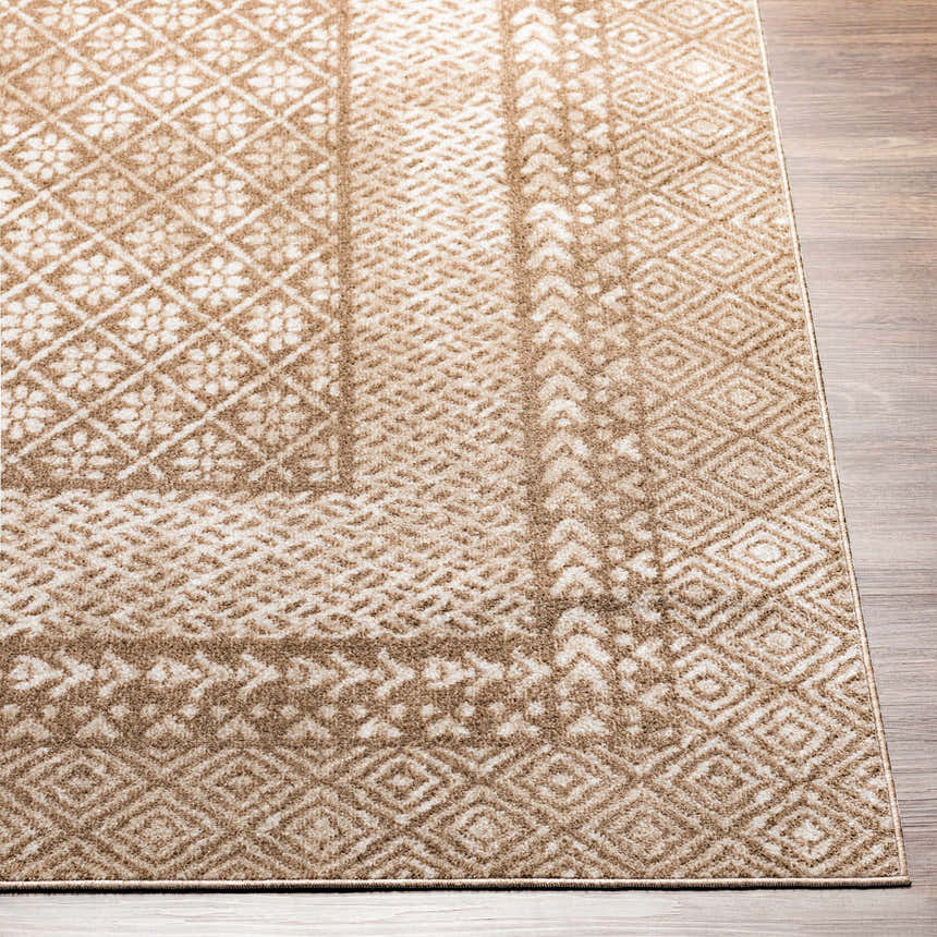 Close-up of the Caditaan Washable Area Rug. Brown, cream, and light beige geometric and floral pattern. Machine woven texture. Front