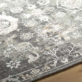 Close-up of the Cantley Handmade Wool Area Rug, showcasing charcoal, cream, and taupe floral pattern and hand-knotted texture. Pile