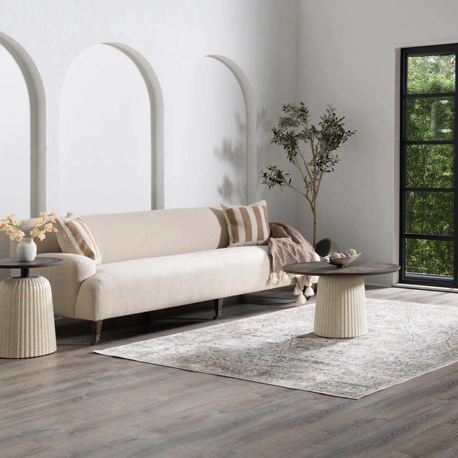 Living room scene with a Manhattan Washable Area Rug in blue, off-white, olive, tan, and yellow under a round coffee table. Roomscene-Rectangle