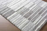 Close-up of the shaggy Carlen Gray Area Rug, with a contemporary gray and ivory striped pattern. Corner
