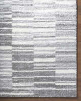 Close-up of the shag Carlen Gray Area Rug, featuring a contemporary gray, ivory, and light gray striped pattern. Corner