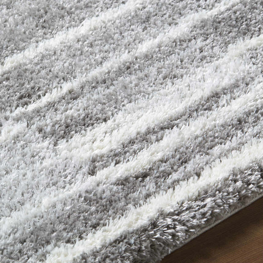 Close-up of the Carlen Gray Area Rug. Shag rug with gray and ivory horizontal stripes. Soft, textured design. Texture