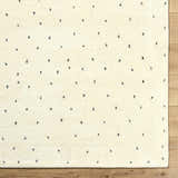 Close-up of the ivory Cirila Dotted Wool Rug showing the charcoal dots and soft, hand-tufted wool texture. Swatch