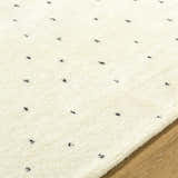 Close up of the ivory Cirila Dotted Washable Wool Rug. Features a dotted charcoal pattern and soft, hand tufted texture. Texture
