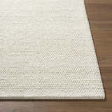 Close-up of the hand-woven Clayne Beige Premium Wool Area Rug; a textured, neutral rug on hardwood floors. Front