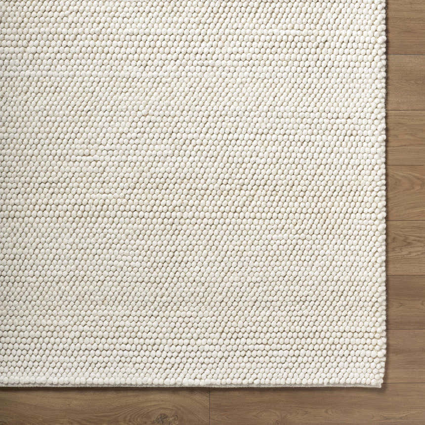 Close up of the beige, hand woven, textured Clayne Premium Wool Area Rug. Corner