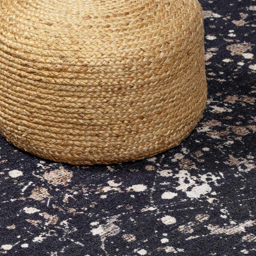 Close-up of Janek Handmade Galey Alix x LIVABLISS GAJA-2300 Area Rug in charcoal, ivory, and taupe with a jute pouf. Styleshot