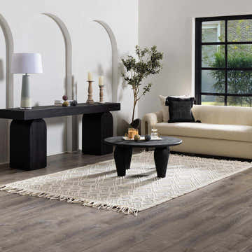 Living room scene with a neutral Arnside D rug, black console table, round coffee table, and cream sofa. Roomscene-Rectangle