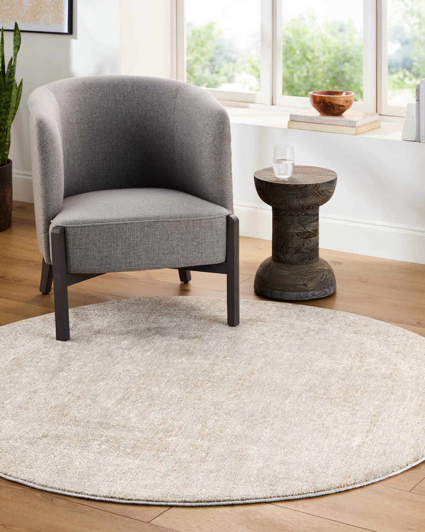 Living room scene with a round, light sage Catrin Area Rug, gray chair, and wood accent table. Roomscene-Round