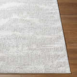 Close-up of the cream and light gray Annisa Area Rug with a subtle geometric pattern on a wood floor. Front