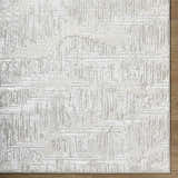 Close-up of the Annisa Area Rug, showcasing its cream, ivory, and light gray contemporary geometric design and textured weave. Corner