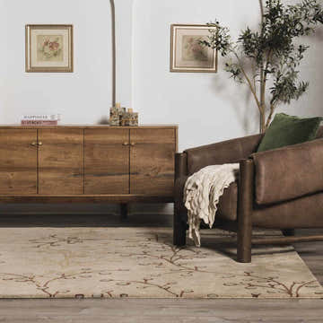 Living room scene with a beige Elsu Wool Rug, brown leather chair, and wooden cabinet. Floral art on the wall. Roomscene-Rectangle