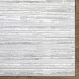 Close-up of the Cardea Area Rug. Cream, ivory, light gray, and white horizontal stripes on a textured, machine-woven rug. Corner