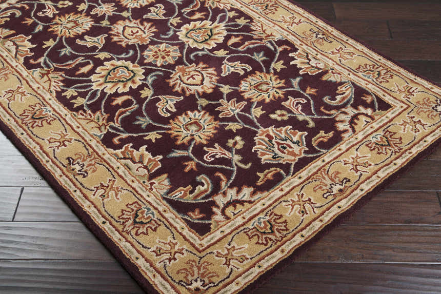 Close-up of the Livabliss Caesar CAE-1024 area rug. Burgundy wool rug with beige floral patterns and a traditional border. Corner