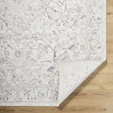 Close-up of the Corina Charcoal Area Rug showing its traditional floral pattern and cream, gray, and charcoal colors. Fold