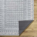 Rainier PNWRN-2313 rug close-up. Machine woven polyester rug with traditional geometric patterns in pale blue, white, and gray. Fold