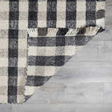 Close-up of the hand-woven Chilliwack Gray Plaid Wool Rug showing charcoal, cream, and gray tones and fringe detail. Fold
