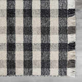 Close-up of Chilliwack Gray Plaid Wool Rug showing charcoal and cream woven squares and fringed edge detail. Swatch