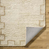 Close-up of the Ciniod Area Rug showing its tan geometric pattern, wool texture, and gray backing on wood floor. Fold