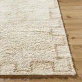 Close up of the hand tufted Ciniod Area Rug, a wool rug in pearl and tan, on hardwood floor. Front