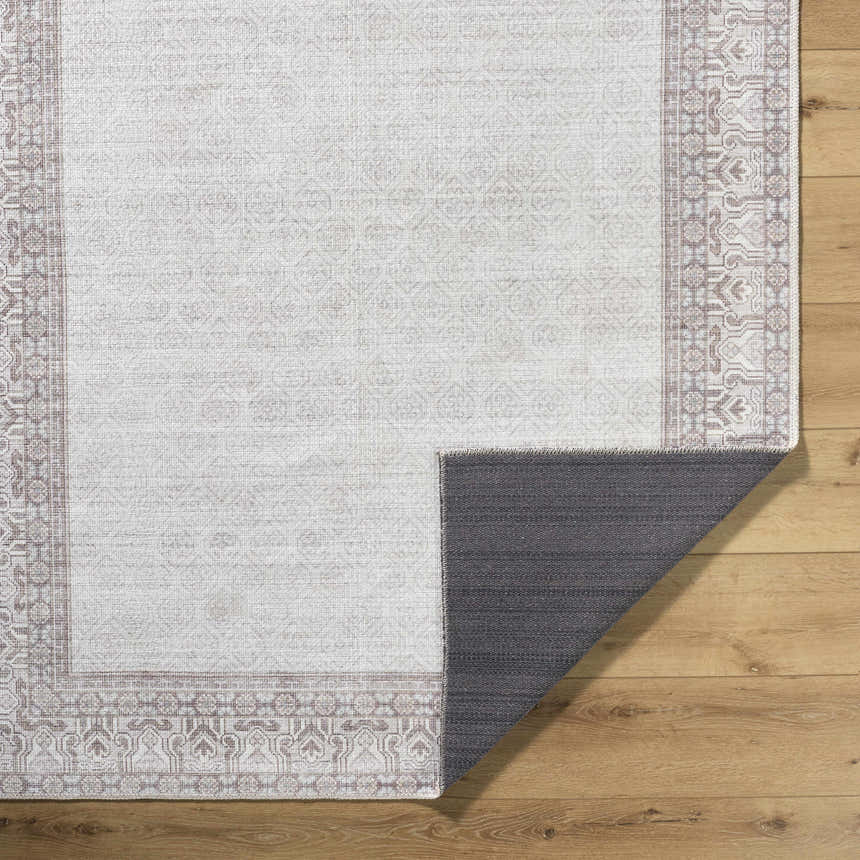 Close-up of Rainier Cottage Border Brown Washable Rug showing cream and brown traditional pattern and non-slip backing. Fold