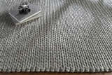 Close up of the hand woven Cirencester Area Rug in medium gray, with a chunky, textured knit design. Styleshot