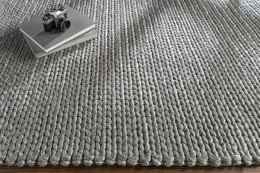 Close up of the hand woven Cirencester Area Rug in medium gray, with a chunky, textured knit design. Styleshot