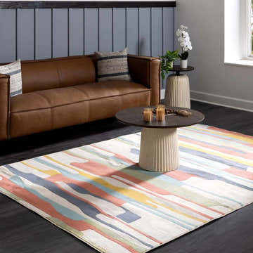 Living room scene with a brown leather couch and the New Southfields area rug with aqua, charcoal, and peach colors. Roomscene-Rectangle