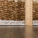 Close-up of the Colson Sage Area Rug showing its pile height and texture next to a basket. Pile