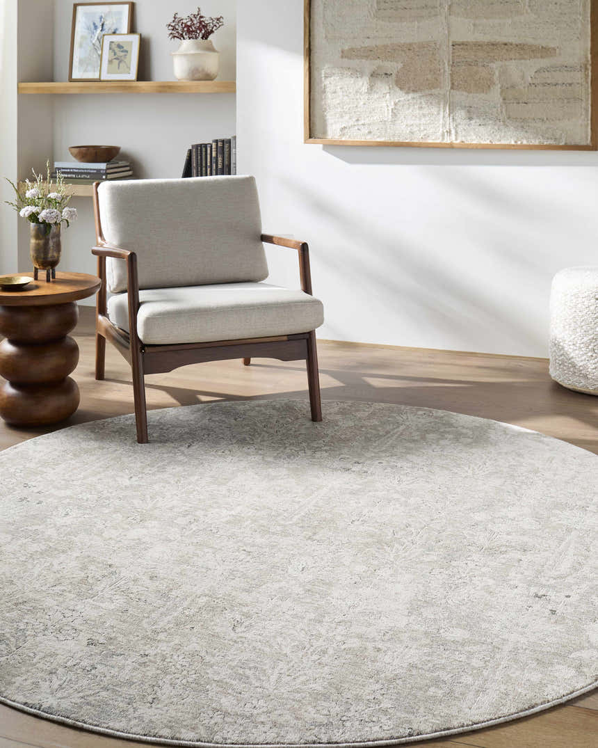 Living room scene with a round Carlyn Area Rug in cream, light sage, and light slate under a chair. Roomscene-Round