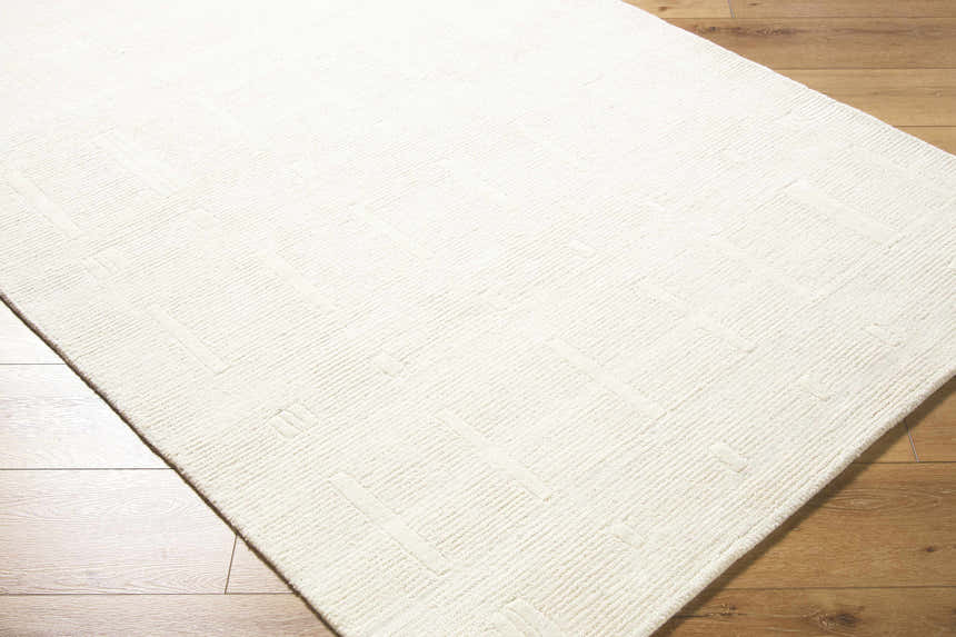 Close-up of the Charan Ivory Cream Area Rug showing its textured, geometric design and soft, off-white color. Corner